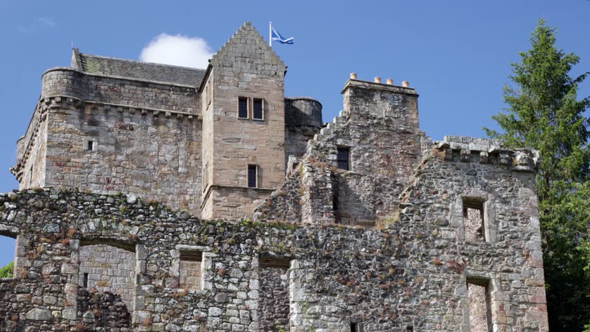 Castle Campbell in Dollar in the Scottish highlands, medieval fort with fortification and ruin in high mountains and forest in Scotland near Edinburgh with flag blowing in wind