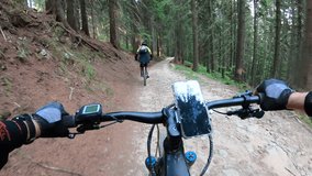 Point of view. Couple of cyclist riding electric mountain bikes in the forest. Smartphone on bicycle handlebar. Concept of adventure, leisure time outdoors. - Powered by Shutterstock - Get 15% off with code: PIKWIZARD15