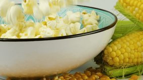 Popcorn grains falling into ceramic bowl isolated on white background. Fresh corn cobs and dried grains near bowl. Slow motion. - Powered by Shutterstock - Get 15% off with code: PIKWIZARD15