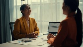 Two businesswomen discussing charts and reports in a professional office setting. Engaging in a collaborative meeting at a desk with documents and a laptop - Powered by Shutterstock - Get 15% off with code: PIKWIZARD15