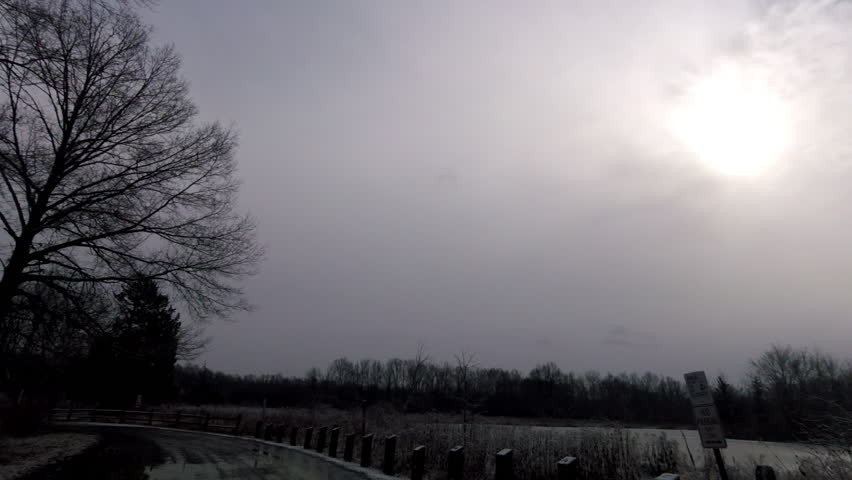 driving county road in park and rural area on snowy day in winter
