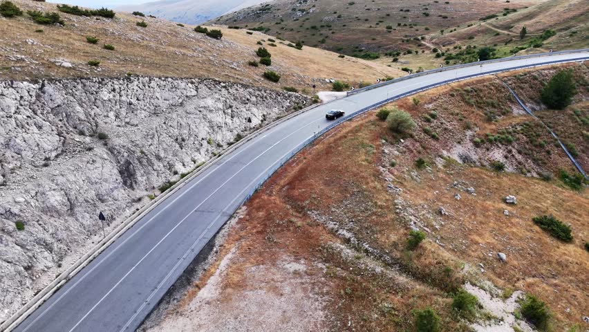 Winding Mountain Road Encircles Scenic Landscape Under Blue Sky in Late Afternoon Light