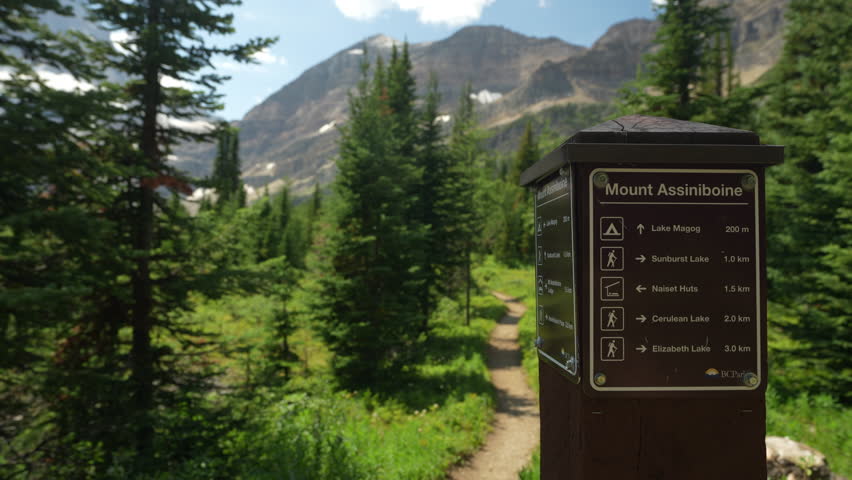 Young Woman on Hiking Trail Passing Sign With Directions. Mount Assiniboine, Canada