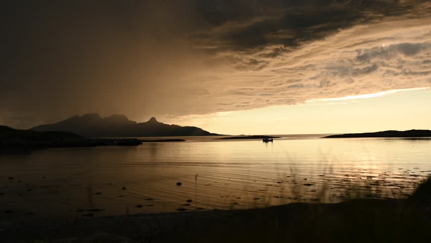 Dramatic evening storm clouds at stunning evening over the beach at Mjelle in Northern Norway pouring rain over the bay
