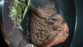 Juicy, golden brown pork belly with a pat of melting butter, garlic and rosemary, pan-fried and turned with tongs. Close-up. Vertical video - Powered by Shutterstock - Get 15% off with code: PIKWIZARD15