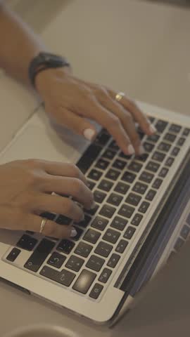 Female hands typing on laptop at desk, close up view