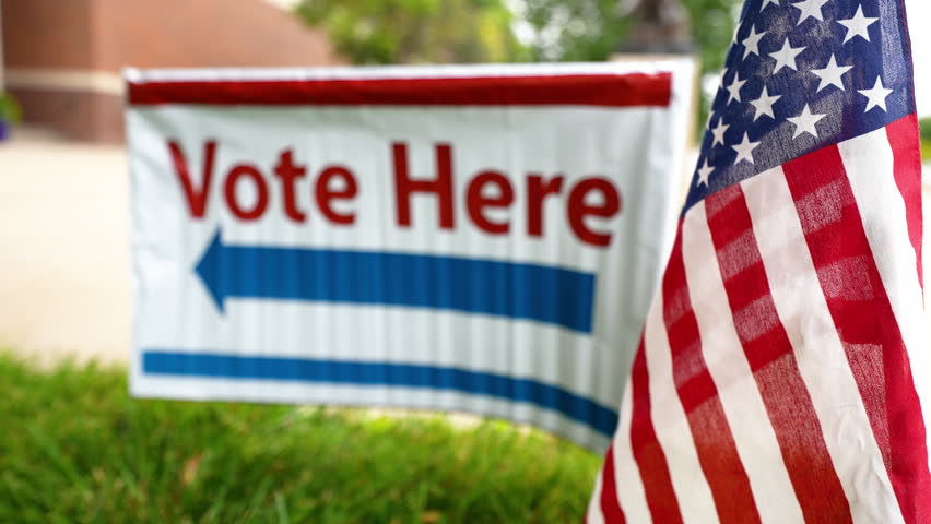 Vote here election sign at local precinct ballot location with American flag