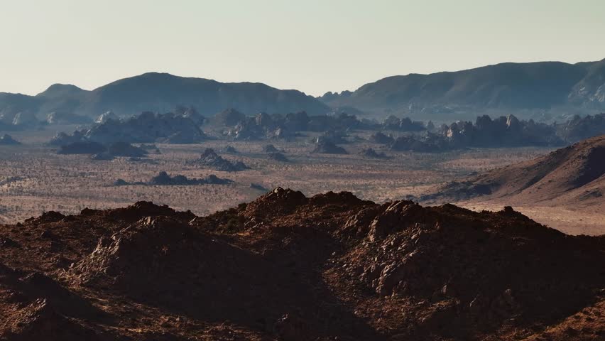 A wide panning aerial view of boulders in the high desert of California