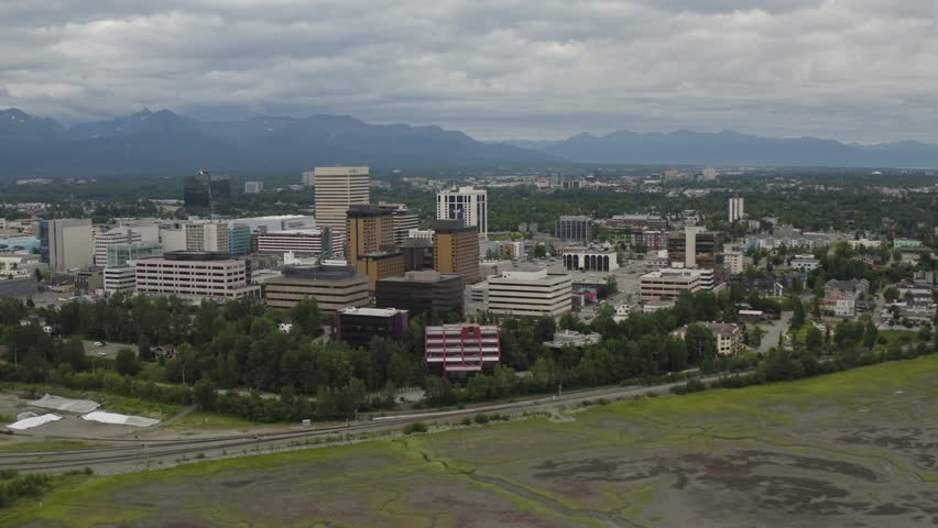Panoramic view of downtown Anchorage, Alaska buildings and waterfront with mountains in distance - 4K Drone