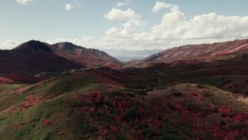 Aerial drone shot of Salt Lake City mountain range with fall-colored leaves at 60fps.