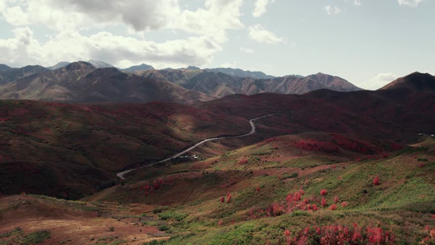 Aerial drone shot of Salt Lake City mountain range with fall-colored leaves at 60fps.