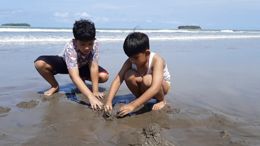 two boys are playing in the sand on the beach