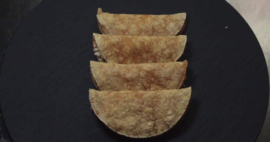 Beautiful shot of a group of 4 chicken tacos or tortillas, a famous Mexican dish cooked in an industrial kitchen in a restaurant.
