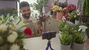 A smiling young hispanic man arranges flowers in a colorful flower shop while recording a video. - Powered by Shutterstock - Get 15% off with code: PIKWIZARD15