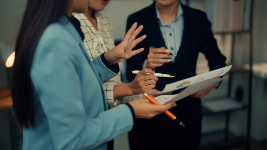 Business professionals collaborate in an office, discussing documents and exchanging ideas, emphasizing teamwork and communication