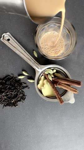 A piping hot Masala tea is being poured in a glass, shot from above angle. The most popular Karak chai is made with ginger, cardamon and other spices. A classic Indian spiced tea. 