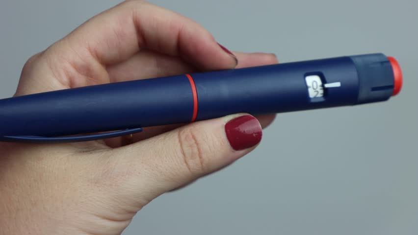 Woman preparing the insulin pen with the needed units of insulin to be applyed. 