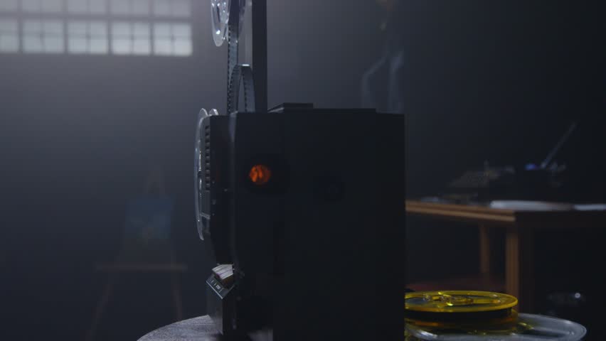 A closeup view of a vintage film projector highlighted by warm light, evoking deep nostalgia in a creative space