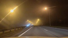 First-person view of a driver driving on a highway at night in fog. Driving on a night road with bright lights and a forest in slow motion. View through driver's window on a foggy road. Summer time. - Powered by Shutterstock - Get 15% off with code: PIKWIZARD15