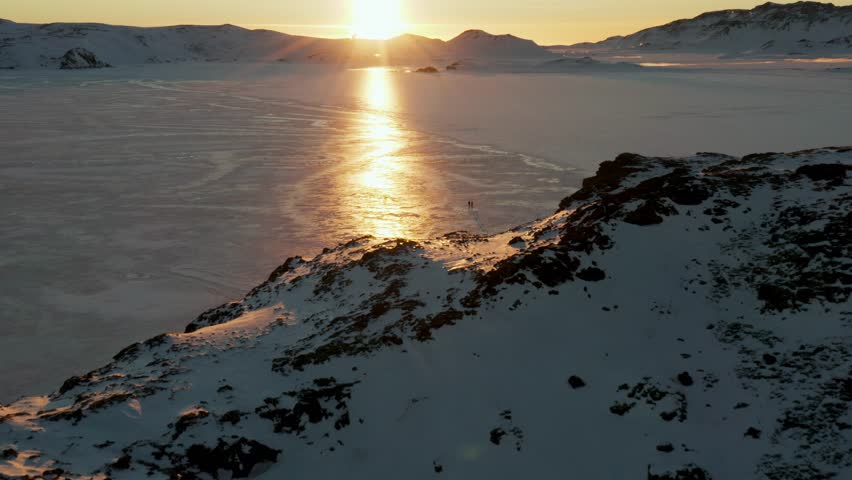 People walking on Frozen Lake with Sunset and Sunray Reflections