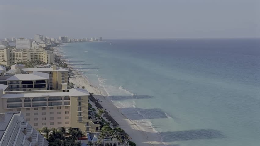 Aerial wide shot of turquoise coastline of Cancun, Mexico in summer. Hotel Buildings and sandy beach. Luxury holiday spot for tourist.
