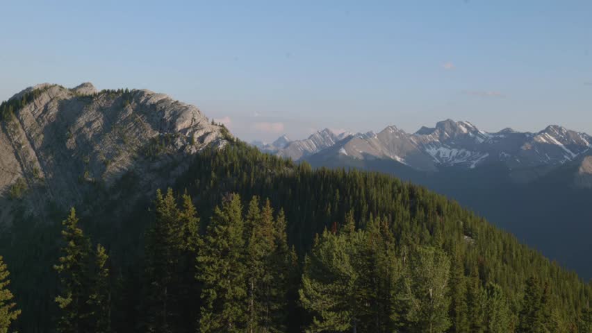 Snow-capped mountains and dense pine forest at sunset in Banff National Park