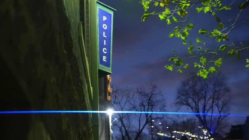 An illuminated police station sign at twilight.