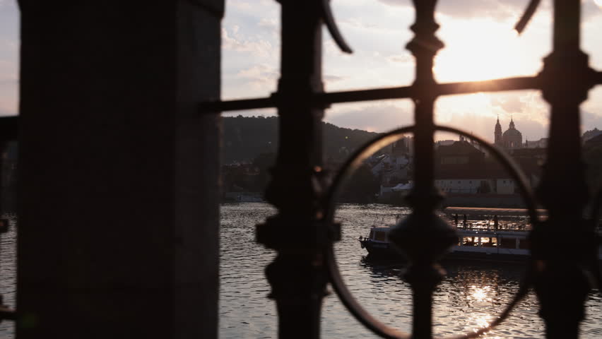 Sun setting behing St Nicholas Church framed by iron fence_Czech Republic