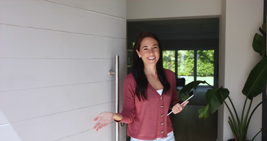 Woman realtor opening door and welcoming clients of agency, came to look at new-built housing for purchase. Real-estate offer, bank loan and new dwelling buy for independence, renting or investments