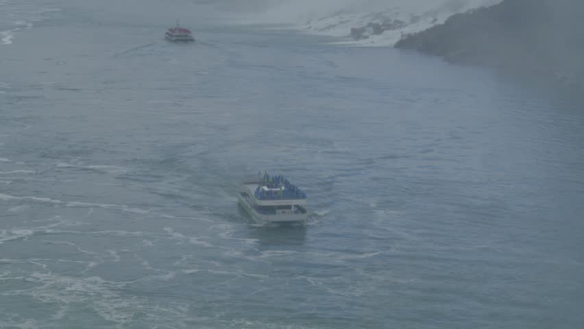 Breathtaking view Niagara Falls in Canada, captured on a cloudy day.Tourist boat filled with a crowd people approaches the powerful falls, adding a sense adventure and excitement to moody atmosphere