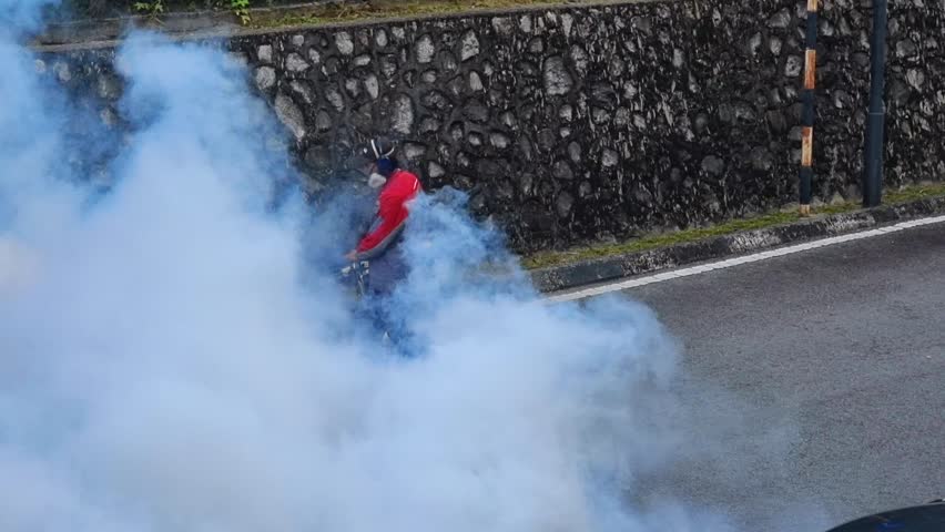 Person fogging insecticides around bushes and drain to kill mosquito larvae to prevent mosquito borne disease like dengue and malaria