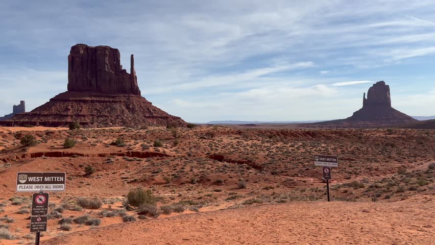 Monument Valley Navajo Tribal Park in Arizona and Utah features the iconic West and East Mitten Buttes red sandstone formations with signs on a beautiful day with blue skies - USA