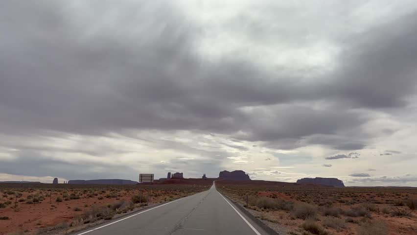 Point of View POV driving shot looking at the road ahead driving towards Monument Valley. The iconic sandstone buttes of this location are seen in the distance. Taken on iconic Highway 163 - Utah, USA