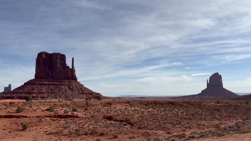 Static shot of the iconic Monument Valley Mittens buttes on a partly cloudy day in Arizona, USA. The breathtaking scenery showcases the majestic beauty and grandeur of the American Southwest.