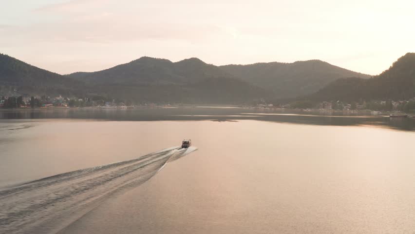 Aerial view of a lake and a boat floating on the water. Lake in a gorge, a boat floating at sunset.
