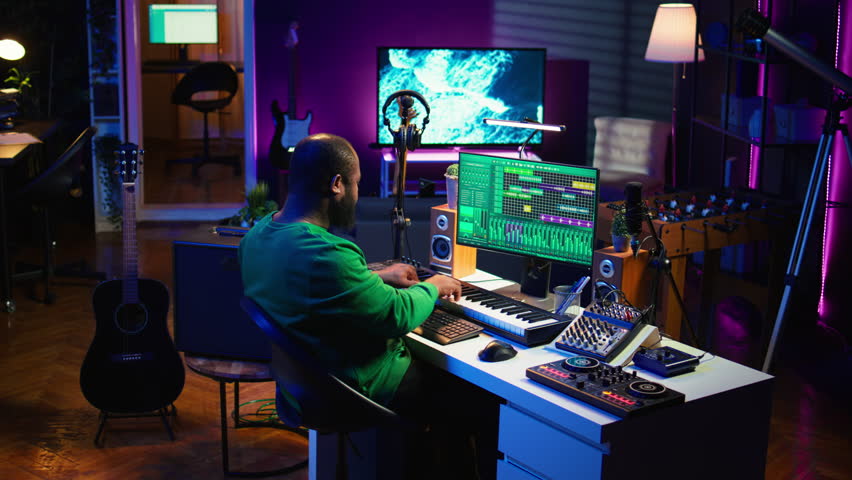 Artist playing electronic piano keyboard notes and recording audio files to use mix and master techniques, editing recordings to edit sound effects. Musician operating on synthesizer gear. Camera B.