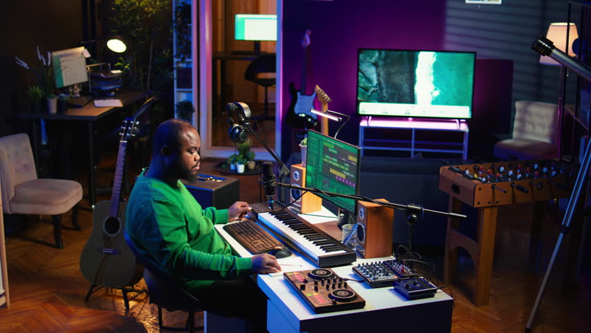 Artist composer recording a new track on his home studio microphone, editing his song with professional gear. Adjusting volume levels and adding sound effects, mix and master. Camera B.