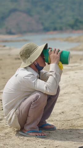 veitnamite mechanic with tran hat rests and drinks water squatting in vietnam