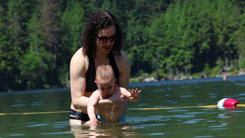 Mother And Baby Play In Lake. Buntzen Lake, Anmore, British Columbia, Canada.