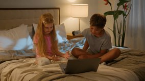 Happy Caucasian kids little siblings smiling family brother boy son daughter girl children watching online video enjoying cartoon movie using modern tech pc laptop computer bed indoors evening bedroom - Powered by Shutterstock - Get 15% off with code: PIKWIZARD15