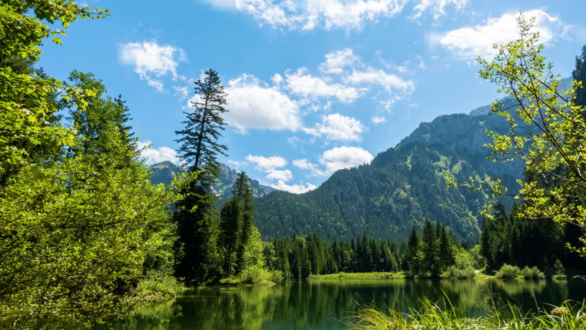 Cloud timelapse against blue sky, mountains and a lake at the Ammergauer Alps, Bavaria, travel Germany