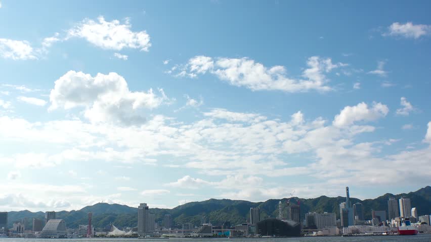 KOBE, HYOGO, JAPAN - JUNE 2024 : Scenery around Kobe port in daytime. View of buildings at Meriken park and Sannomiya downtown area. Travel and tourism concept video. 4K time lapse shot.