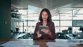 Young latin Hispanic professional business woman working on touchscreen computer app. Middle eastern businesswoman holding digital tablet using tab application sitting at desk workplace in office - Powered by Shutterstock - Get 15% off with code: PIKWIZARD15