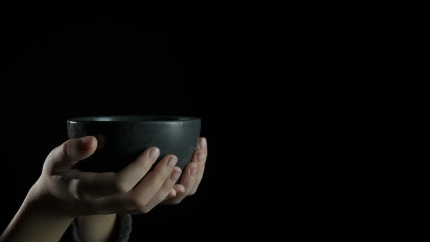 Give porridge to poor child. a person give porridge to little beggar against black background.
