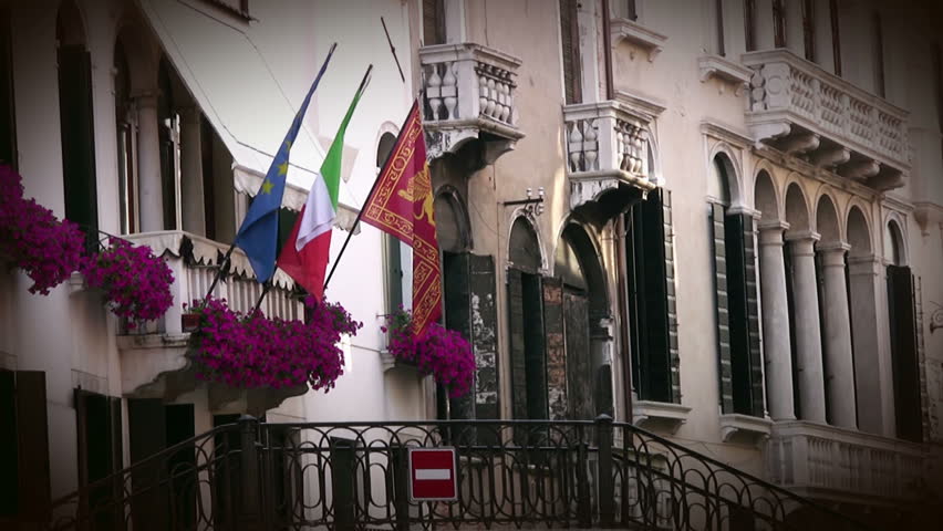 Venice. The narrow street. On the balcony of the building - the flowers and
