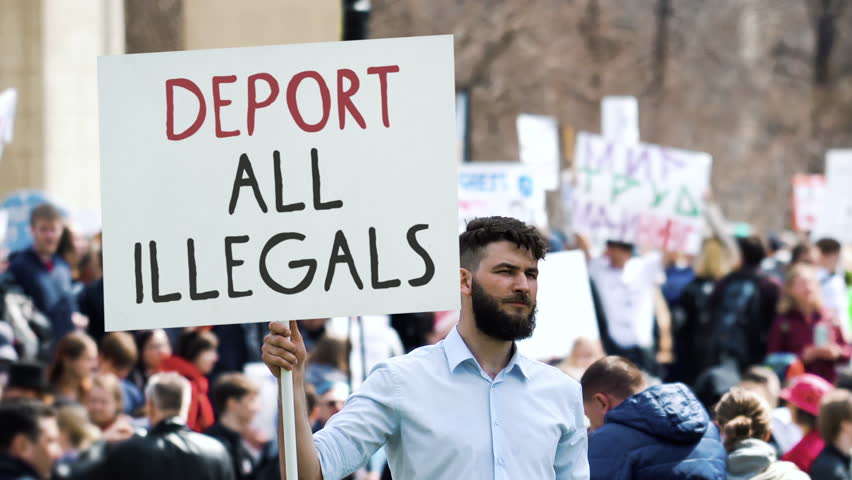 Angry man hold deport all illegals banner. Immigration crisis protest. Crowd wave placard. Stop no immigrants deportation. Anti migration demonstration. Guy against migrants. Refugee march city street