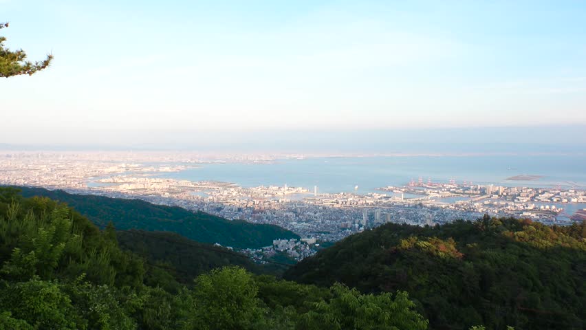 KOBE, HYOGO, JAPAN -JUN 2024 : Aerial high angle view of Kobe city and Kobe port in sunset. View of buildings and street around Kobe port tower and Sannomiya station. 4K time lapse shot, dusk to night