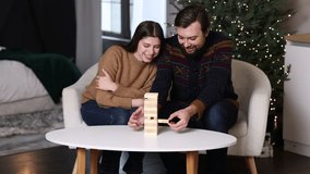 loving young couple 25-30 years old playing game Jenga white coffee table. woman smiling. man reaching for block. focus on his next move. concept: board games home during christmas winter holidays  - Powered by Shutterstock - Get 15% off with code: PIKWIZARD15