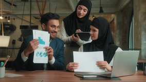 Muslim women hijab female businesswomen Indian man male businessman stock trader agent broker talking video call laptop online conference in office point to graph chart document business negotiation - Powered by Shutterstock - Get 15% off with code: PIKWIZARD15