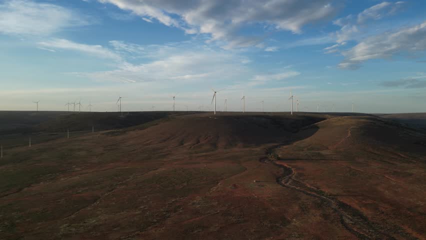 Drone Flies Towards a Windmill Parkt. Aerial View of a Wind Energy Farm With Wind Turbines. Wind Power Turbines Generating Clean Renewable Energy for Sustainable Development.